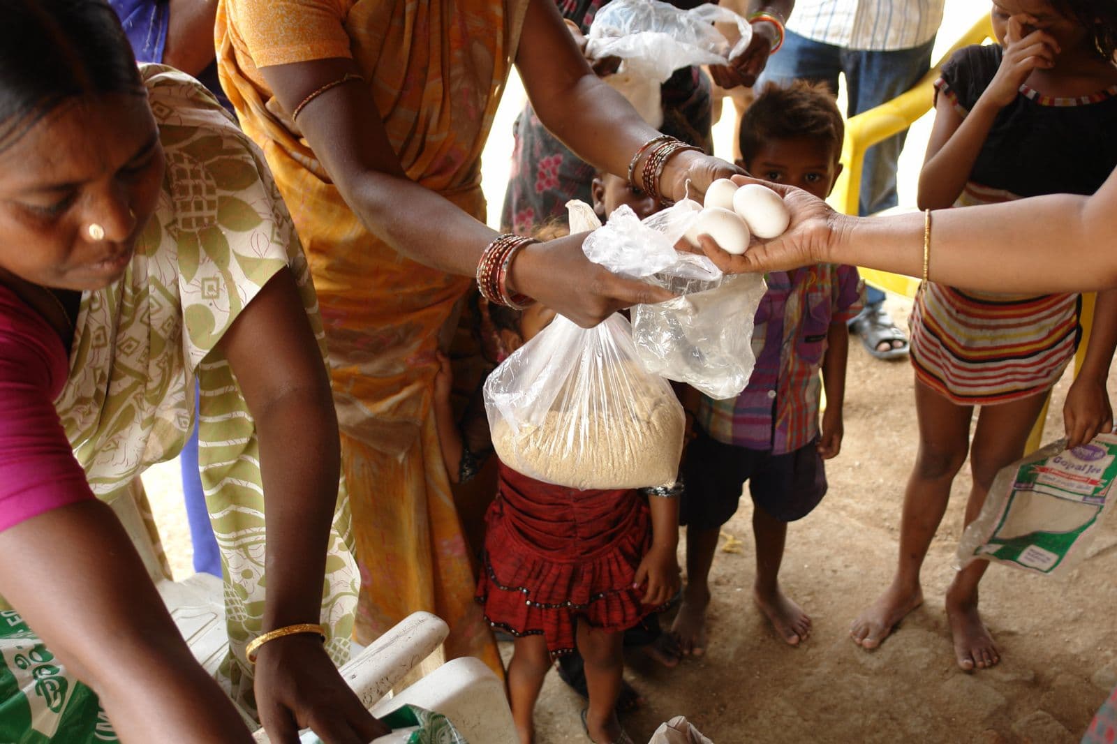 Volunteers handing food items to families during a ration distribution drive