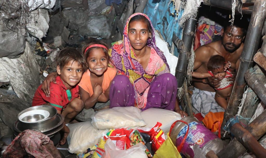 A family in their home with the monthly ration supplies we delivered